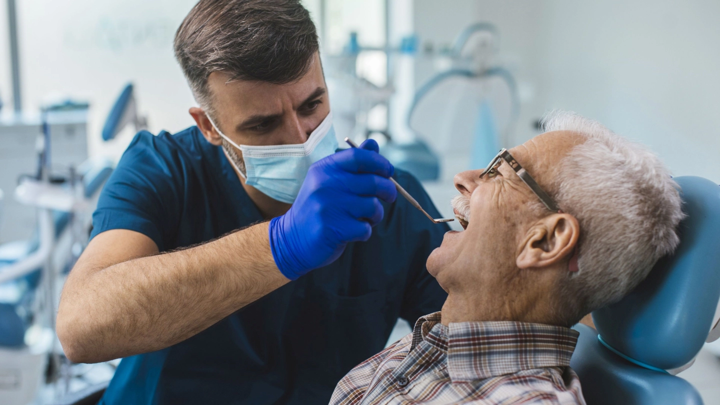 Älterer Mann wird vom Zahnarzt untersucht.