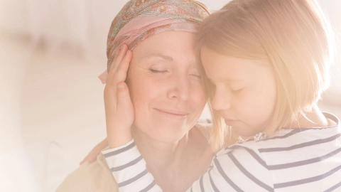 Eine Frau mittleren Alters trägt ein Kopftuch, sie umarmt ein Mädchen.
