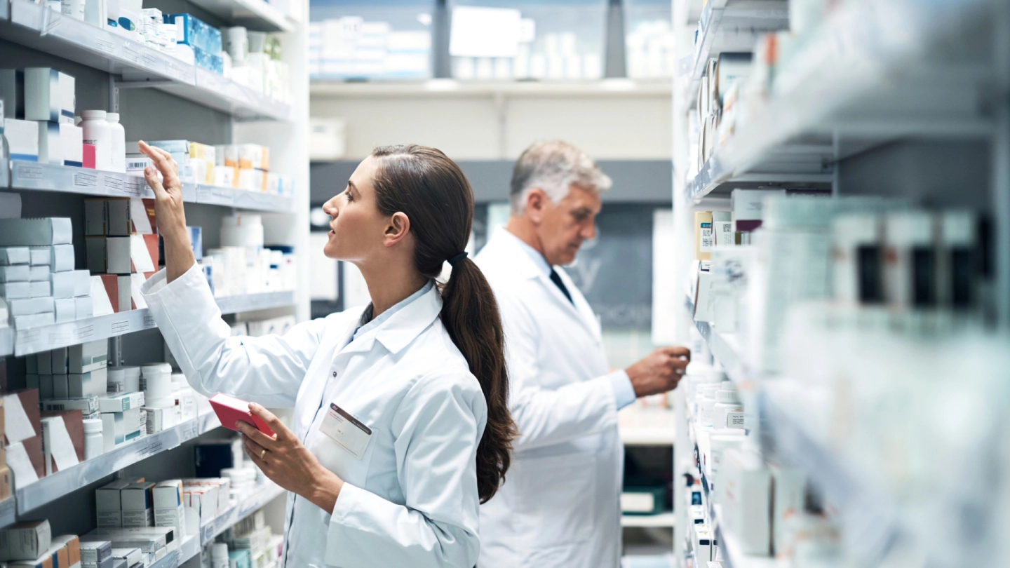 Two pharmacists stocking shelves with medication.