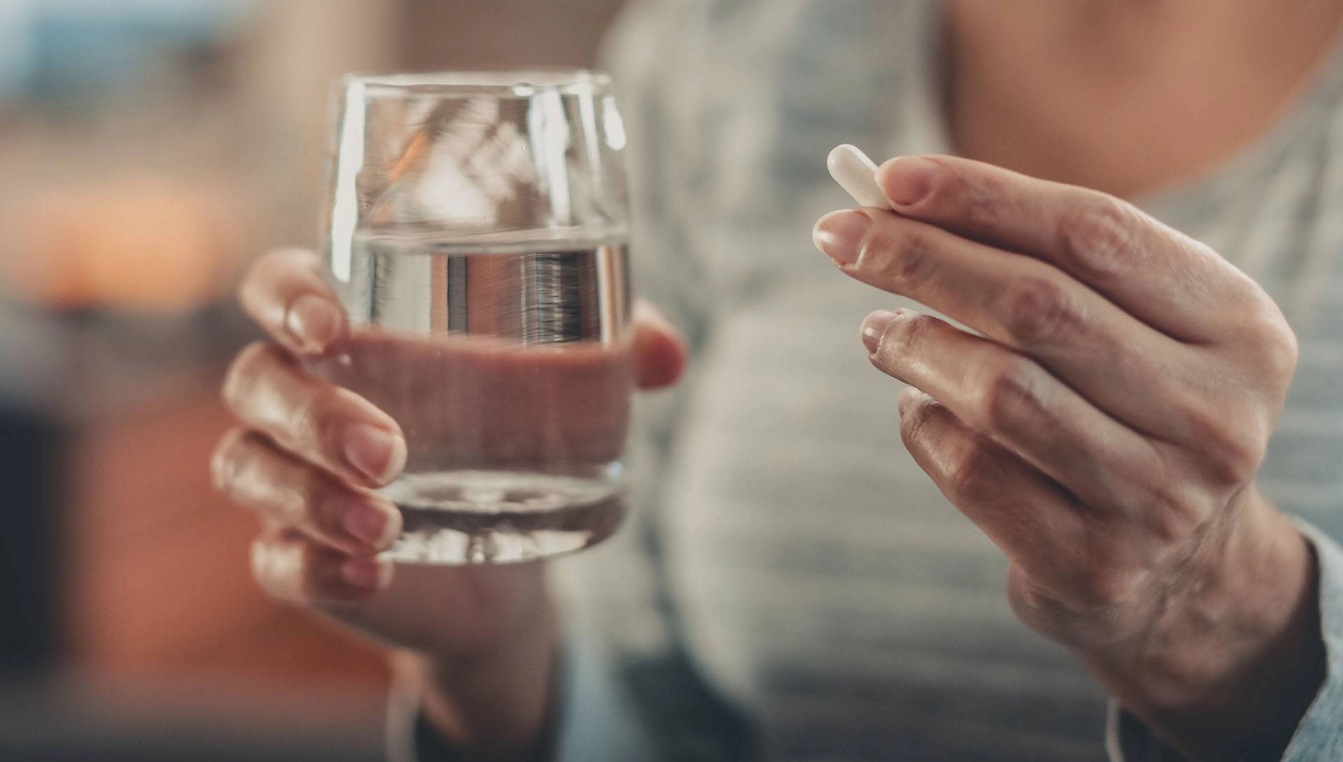 Eine Frau hält ein Glas Wasser und eine Tablette