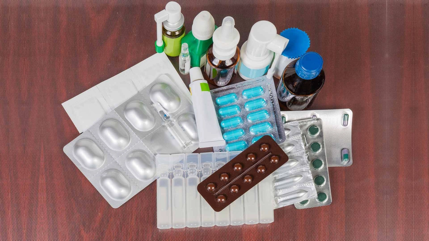 A collection of various types of medication – a blister pack of pills, sprays, drops, suppositories, patches, creams.