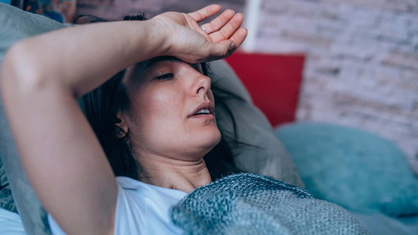 Eine Frau liegt erschöpft auf der Couch.