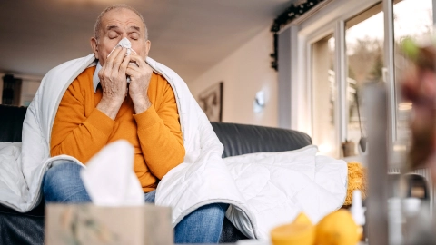 Ein Mann sitzt mit Erkältung zu Hause.