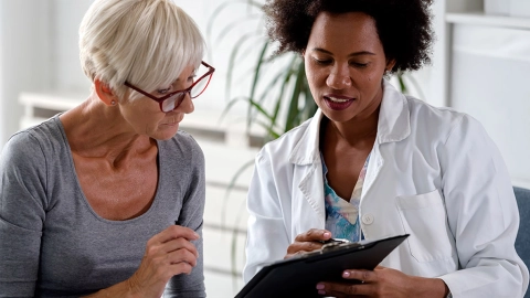 Eine Ärztin erklärt einer Patientin etwas und zeigt dabei auf ihre Unterlagen. 