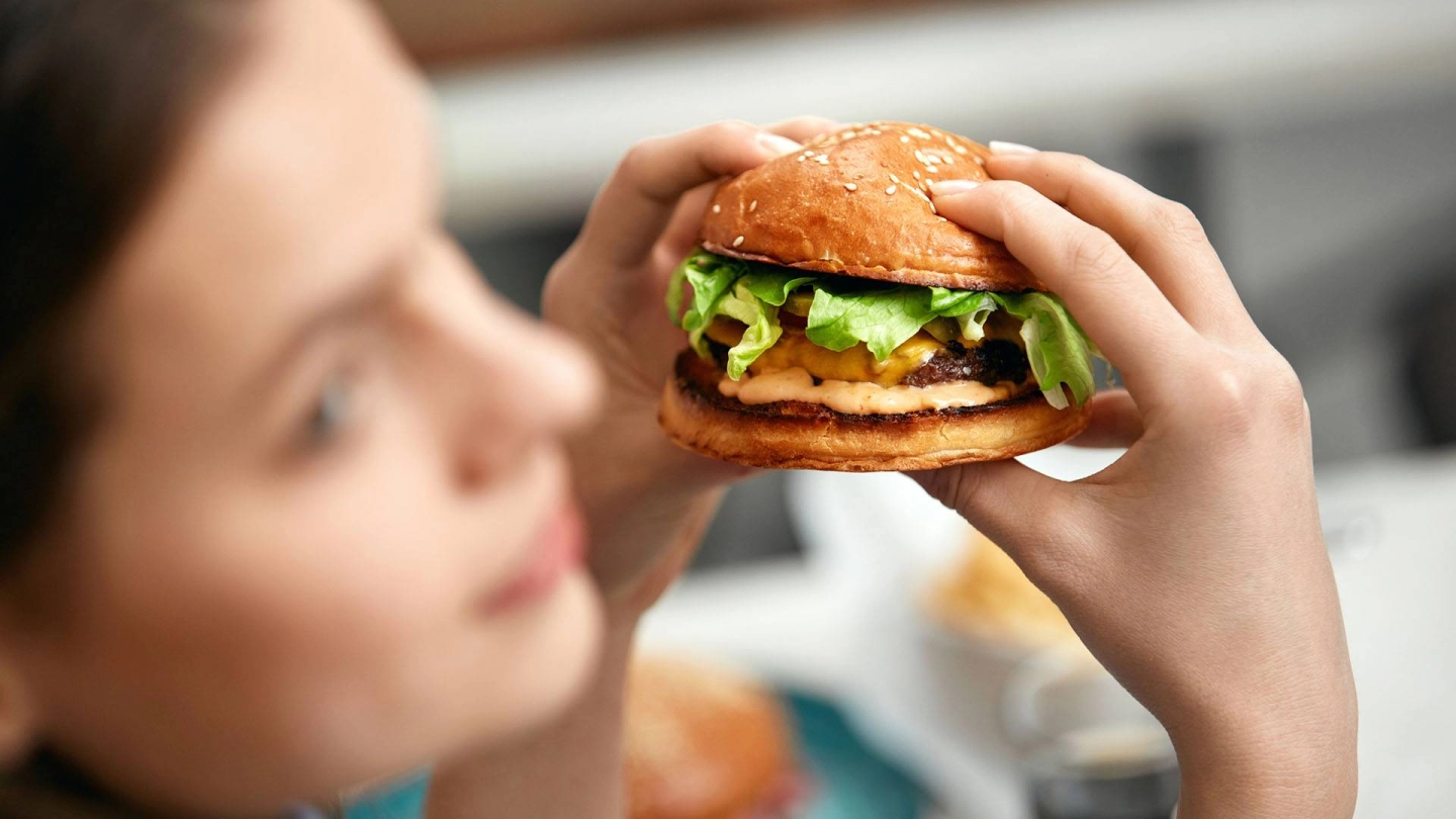 Молодая женщина с гамбургером