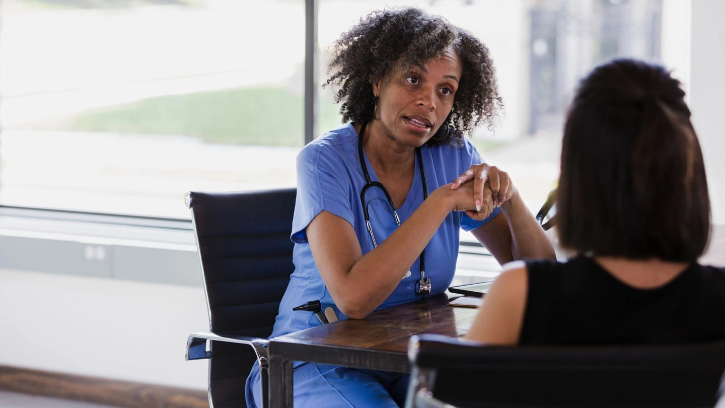 Рак яичников: врач и пациентка сидят за столом. Врач беседует с пациенткой.