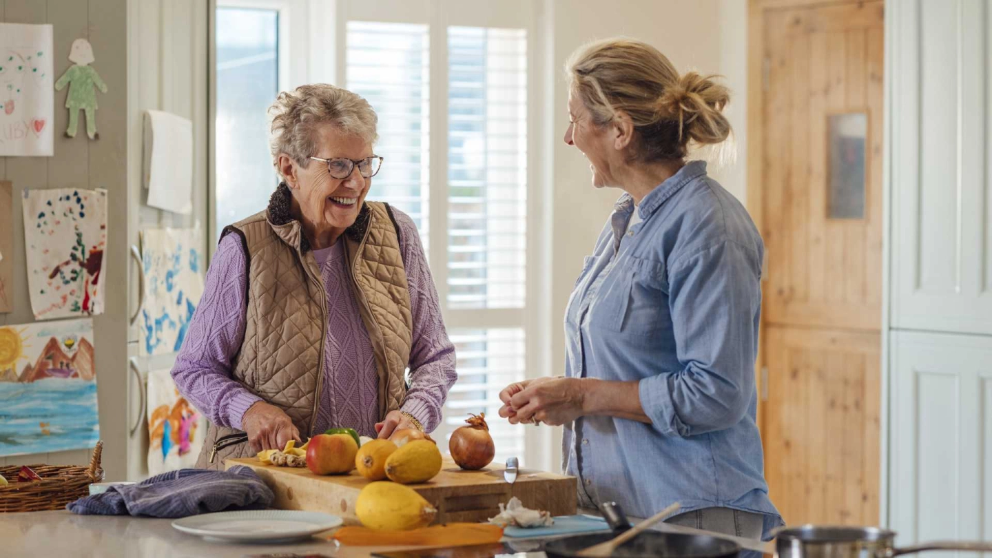 Patientin und Ergotherapeutin bereiten Lebensmittel in der Küche zu.