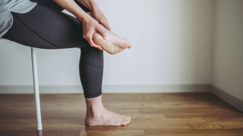 Eine Person fasst sich im Sitzen an die Fersen