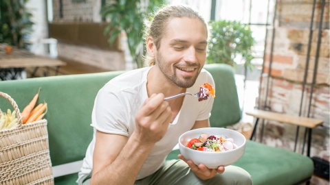 Ein junger Mann isst einen Salat.