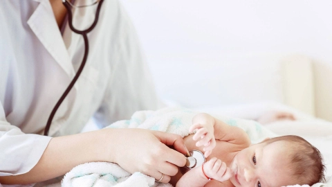 Ärztin hört das Herz eines Säuglings mit einem Stethoskop ab.