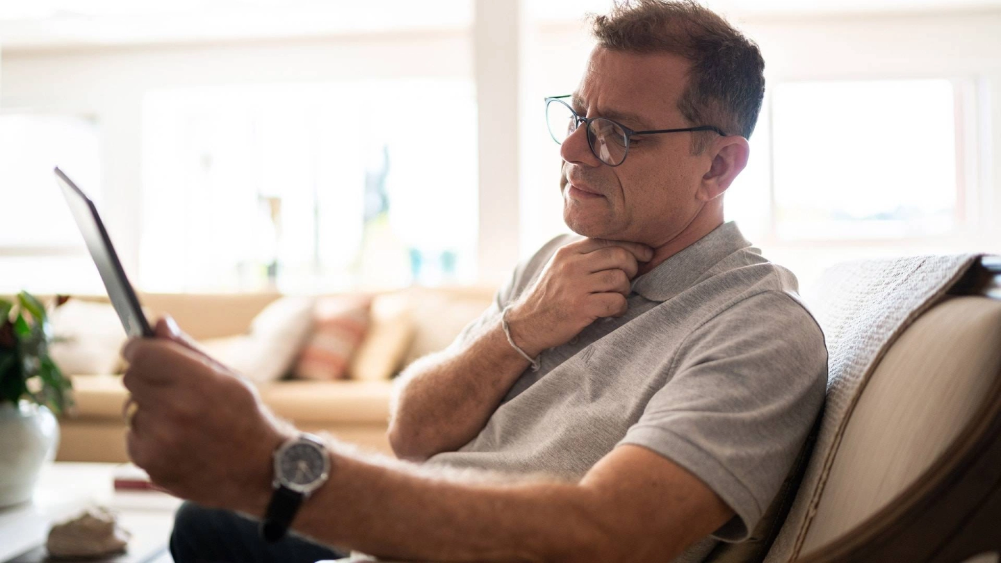 Мужчина среднего возраста держится за гортань.