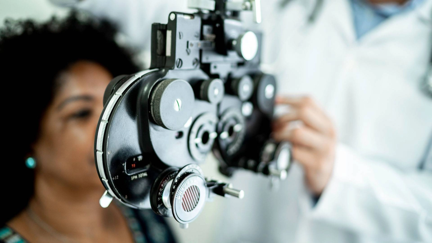 Eine Frau sitzt hinter einem Messgerät für einen Sehtest.