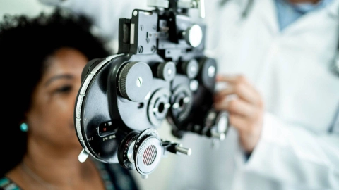 Eine Frau sitzt hinter einem Messgerät für einen Sehtest.