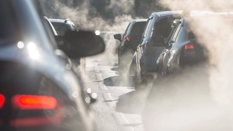 Nahaufnahme von Autos im stockenden Verkehr und Abgaswolken.