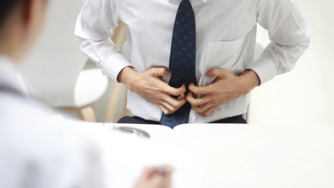 Magenkrebs: Ein Mann greift sich mit beiden Händen an den Bauch. Er scheint starke Schmerzen zu haben.