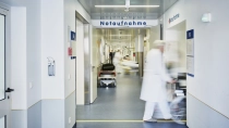Krankenhauspersonal schiebt einen Patienten im Rollstuhl über den Gang der Notaufnahme