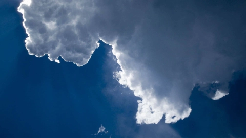 Der blaue Himmel wird von einer weißen Wolke verdeckt, hinter der die Sonne hervorscheint.