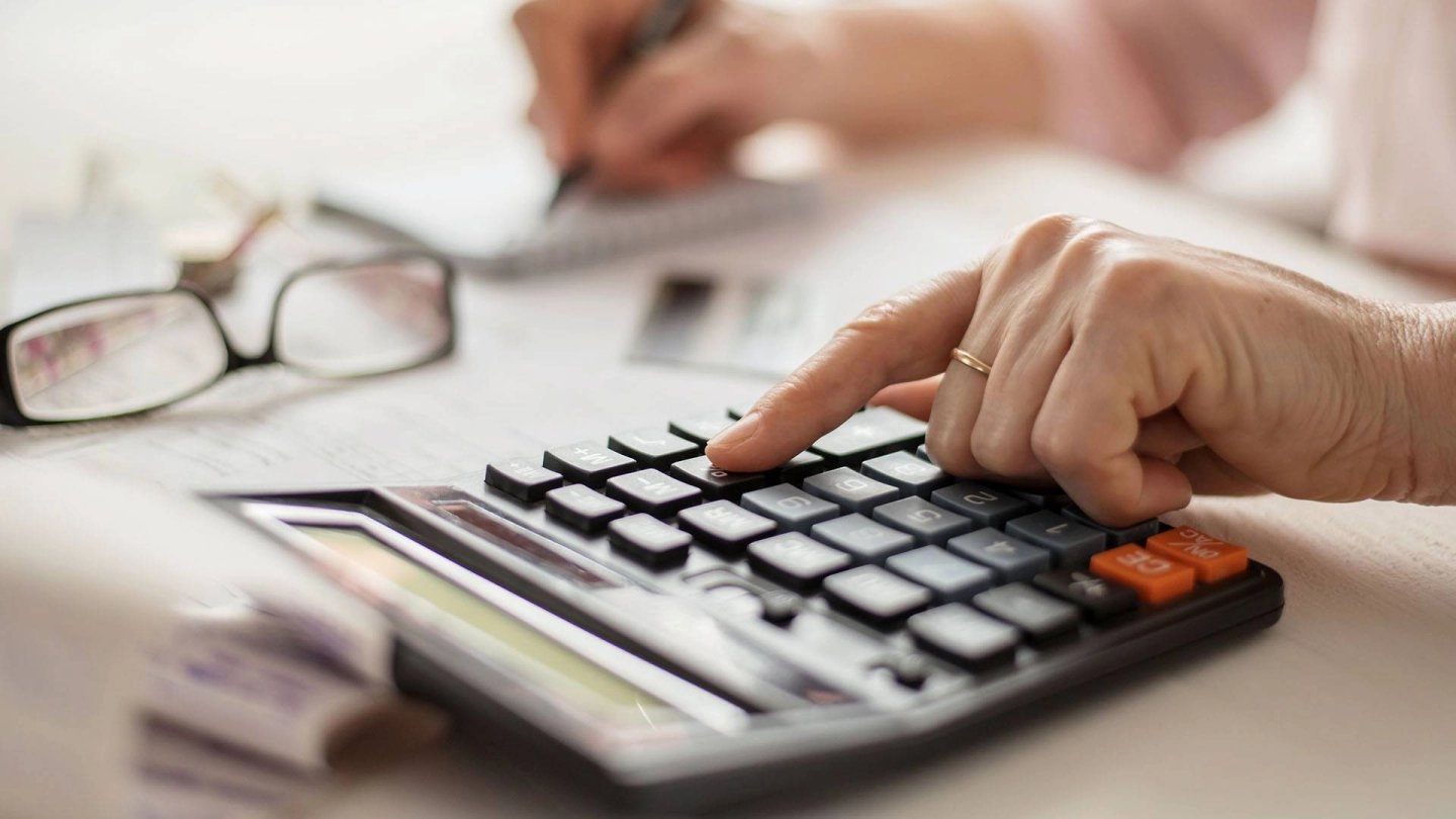 Eine Frau tippt in einen Taschenrechner