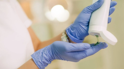 Eine Frau mit Einmalhandschuhen trägt ein Gel auf. 