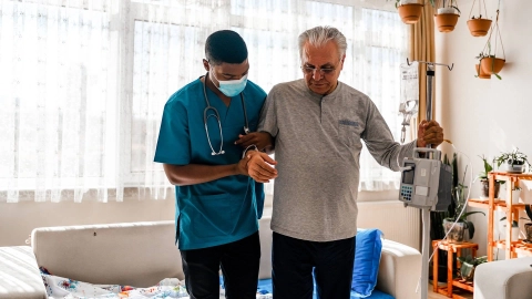 Ein Gesundheitsbesucher hilft einem Senioren bei einem Hausbesuch.