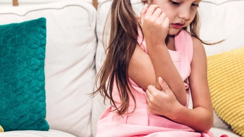 Kleines Mädchen kratzt sich am Arm.