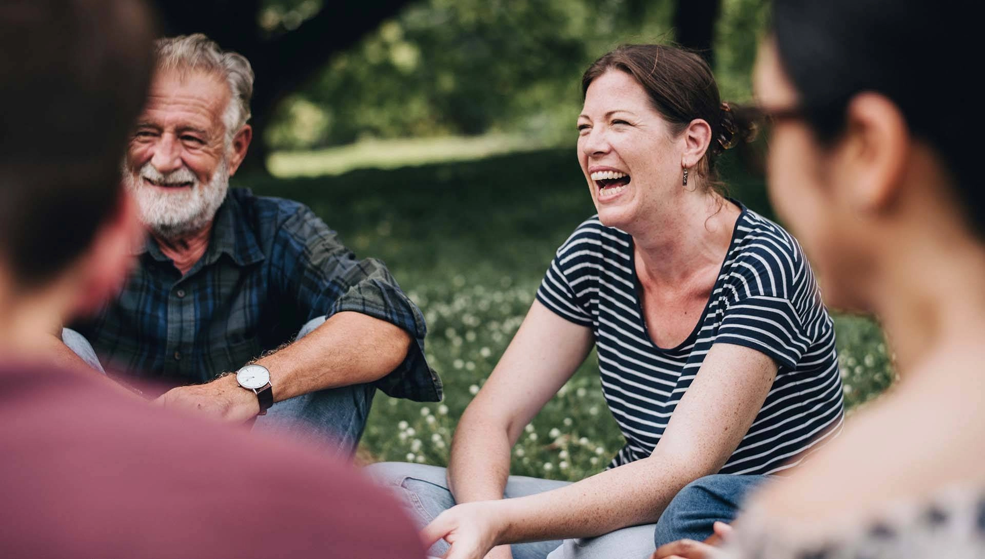 Eine Gruppe sitzt lachend auf einer Wiese