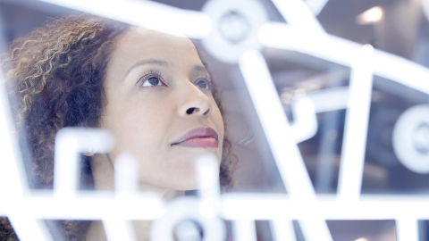 Telematikinfrastruktur: Eine Porträtaufnahme einer Frau, die auf ein digitales medizinisches Interface schaut.