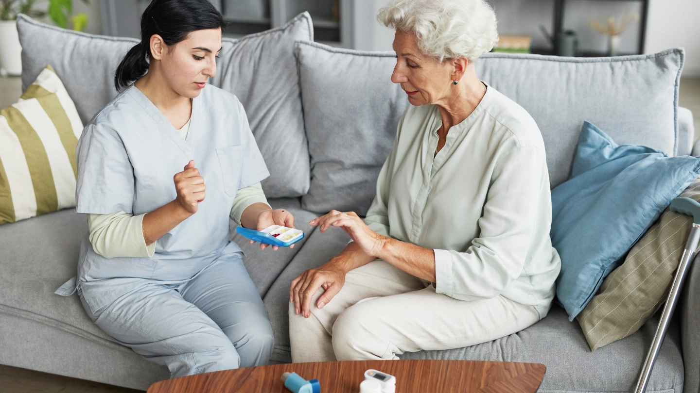 امرأة مسنة ومقدم رعاية يفحصان جهازًا لوحيًا.