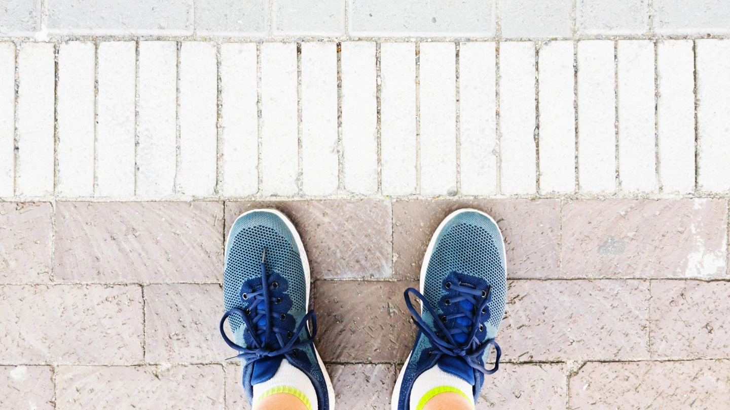 Person steht an akkurat ausgerichteten Pflastersteinen.